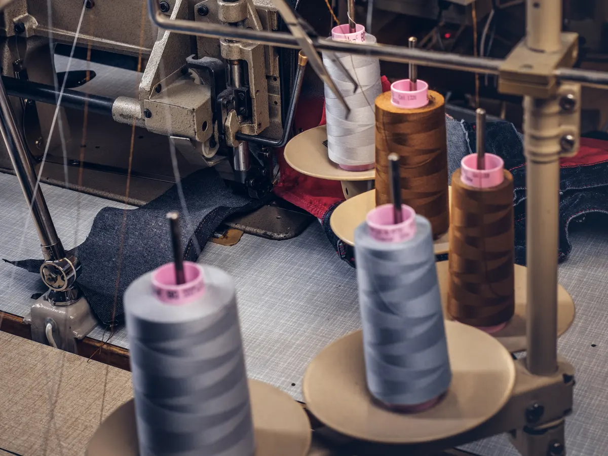 Machine operator stitching a garment panel in the AZLABIN workshop